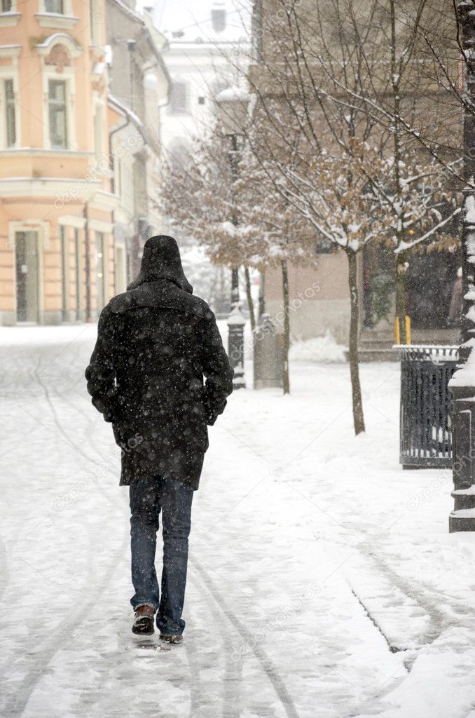 Man walking down the snowed city alley.