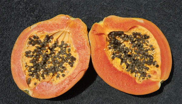 Olgun taze papaya koyu gri arka plan üzerinde ikiye böldüm.