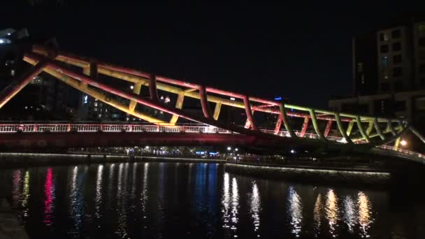 Moderno puente y luces nocturnas de la ciudad reflejándose en el río — Vídeos de Stock