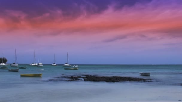 Rödaktig solnedgång över havet; liten båt förbi — Stockvideo