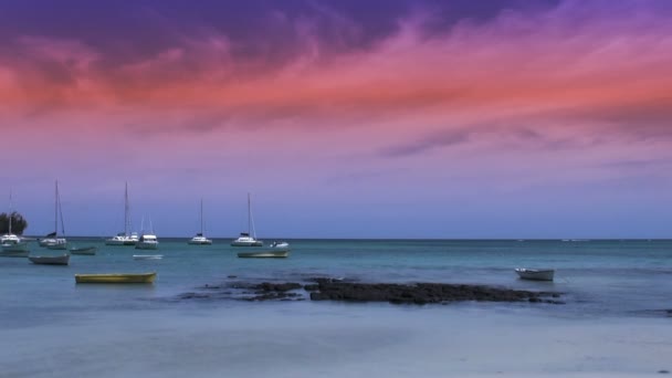 Reddish sunset over the ocean; small boat passing by — Stock Video