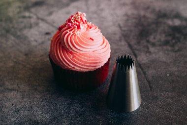 Lezzetli kekler. Krema için kapkekler ve şekerleme eklentileri. Kekler beton bir masada. 