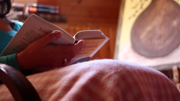 Una ragazza ha letto un libro su una vecchia sedia a dondolo — Video Stock