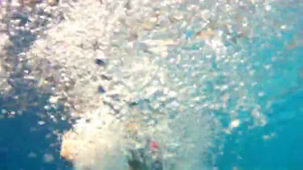 Un bambino nuota in una piscina come una naiade, la telecamera va sott'acqua e mostra come galleggia — Video Stock