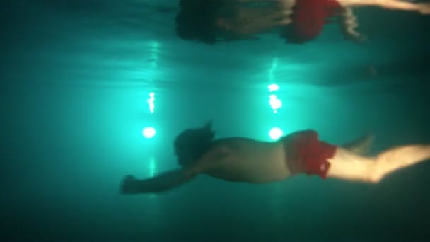 Man simma under vattnet i poolen på kvällen. Underwater skott. — Stockvideo