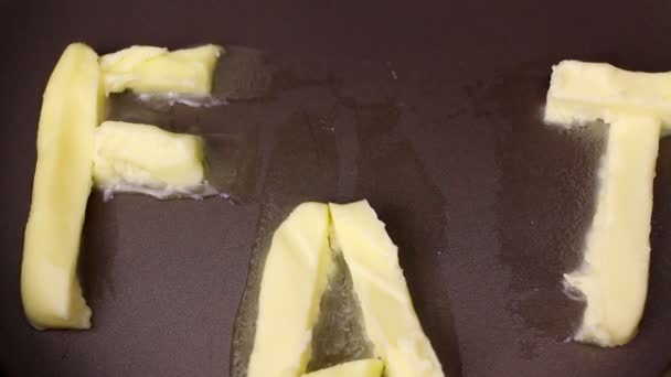 La parola grasso fatto di margarina si scioglie in una padella calda — Video Stock