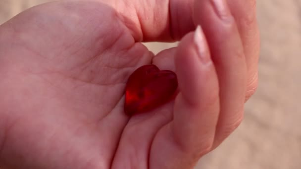 Corazón de cristal rojo en el mar y el surf. Corazón en la palma — Vídeo de stock