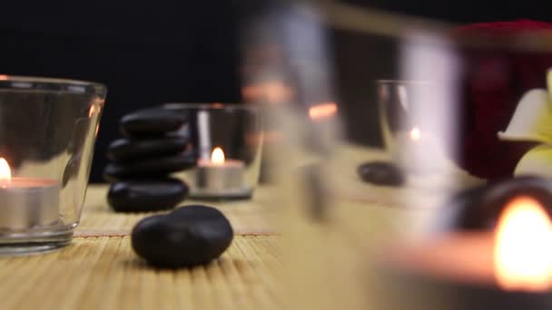Black spa therapy stones surrounded by candles — Stock Video
