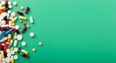 Yeşil arka planda beyaz haplar. Farklı boyutlarda ve şekillerde haplarla dolu cam kavanoz. - Evet. Yüksek kalite fotoğraf