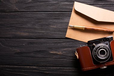 Üzerinde yazı olan bir zarf, güzel bir kamera ve siyah ahşap arka planda köpüklü bir fincan kahve. Yüksek kalite fotoğraf