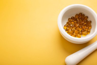 Sarı arka plandaki kaplarda vitamin ya da haplar. Mesaj için yer. Yüksek kalite fotoğraf