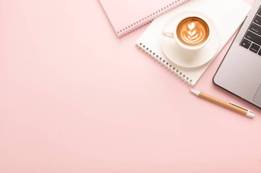 Not defteri, güzel desenli bir fincan kahve ve pembe arka planda bir not defteri. Mesaj için yer. Yüksek kalite fotoğraf