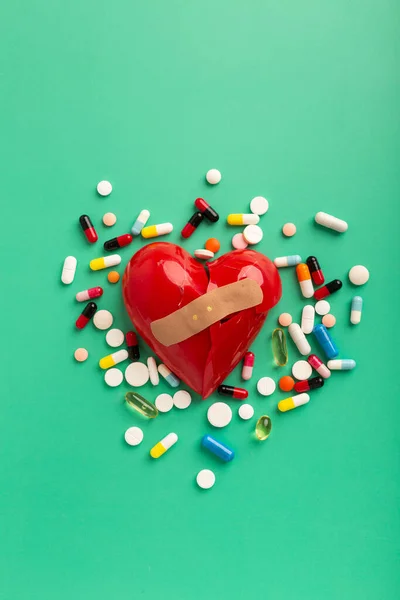 Heart broken pills and phonendoscope on turquoise background. High quality photo