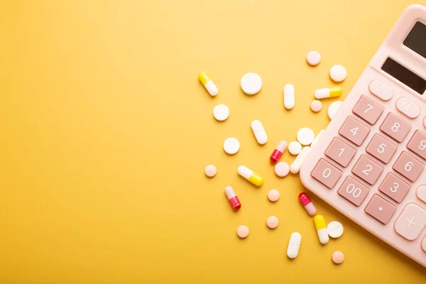 Pink beautiful calculator and vitamins or pills on a yellow background with a place for an inscription. High quality photo