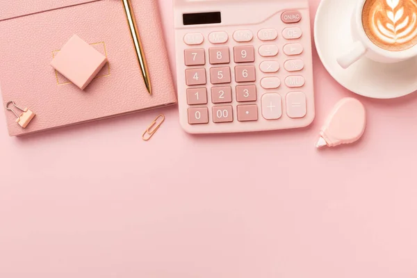 Office pink table, notepad, keyboard, flowers, coffee, hat, notebook, stationery on pink background. Business minimal concept for women. Flat lay, top view, copy space. High quality photo