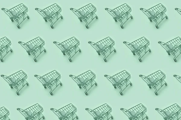 Mini shopping carts, mini shopping carts creative pattern background, top view, isolated on green. High quality photo