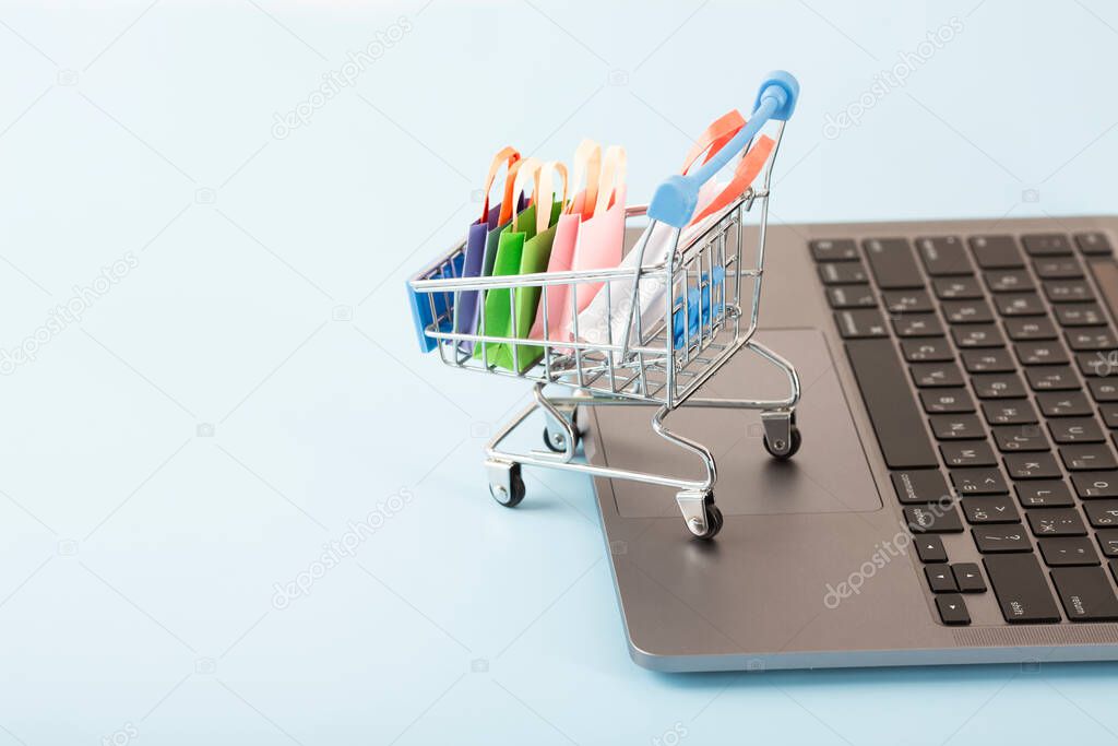 Online shopping concept. Shopping cart, small boxes, laptop on the desk. High quality photo