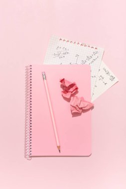 On a pink background, pink school supplies, a calculator, cheat sheets. High quality photo