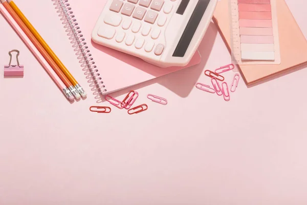 On a pink background, pink school supplies, a calculator, cheat sheets. High quality photo