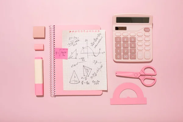 On a pink background, pink school supplies, a calculator, cheat sheets. High quality photo