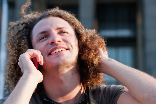 Junger Mann mit lockigem Haar spricht auf Handy — Stockfoto