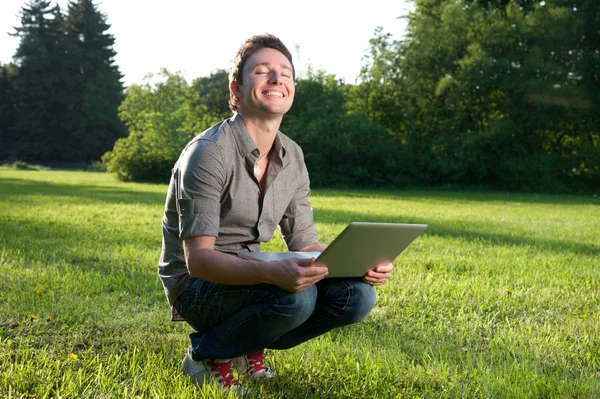 Człowiek uśmiecha się z laptopa — Zdjęcie stockowe