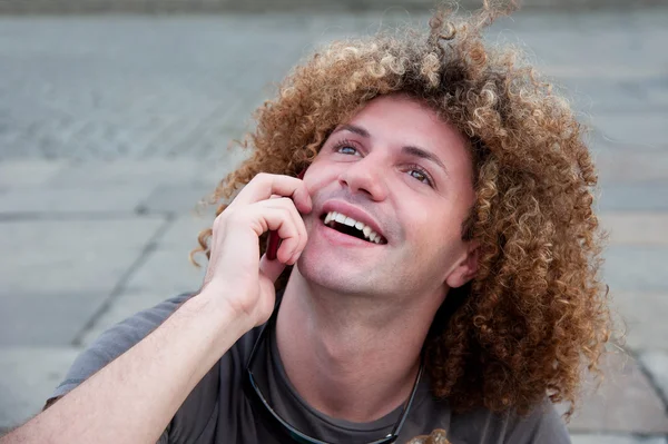 Kıvırcık saçlı genç adam cep telefonunuzun konuşma — Stok fotoğraf