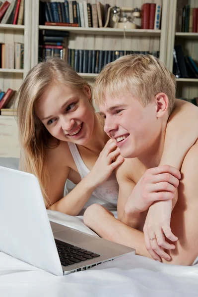 Chica y niño acostado en la cama con el ordenador portátil — Foto de Stock