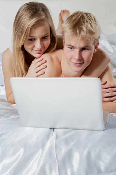 Mädchen und Junge liegen mit Laptop im Bett — Stockfoto