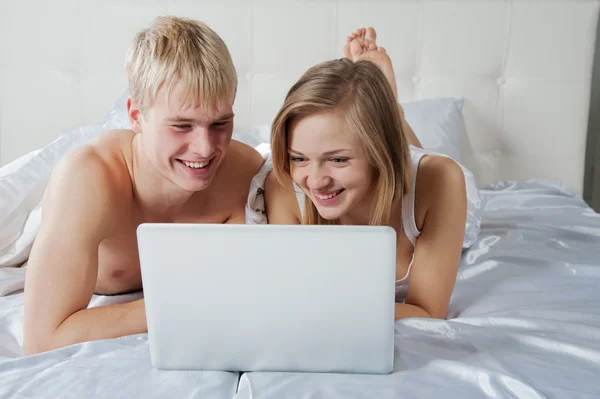 Dívka a chlapec leží v posteli s notebookem — Stock fotografie