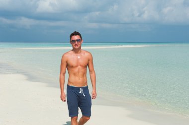 insan mavi deniz ve güzel gökyüzü ile sahilde yürüyor.