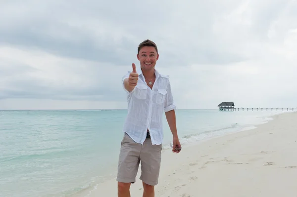 Man shows the thumb on the beach near the sea — Stock Photo, Image
