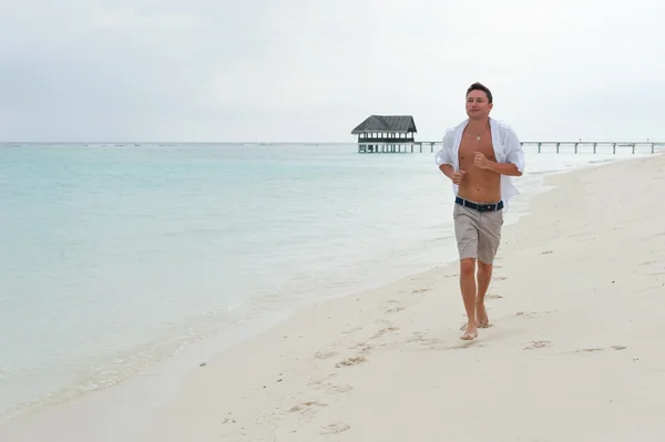 El hombre corre por la playa en el fondo del mar — Foto de Stock