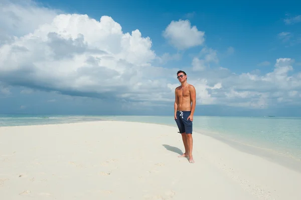 Hombre se encuentra en la playa con el mar azul y el hermoso cielo —  Fotos de Stock