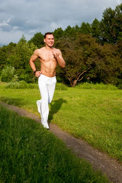 Muž v bílých kalhotách běží na silnici — Stock fotografie