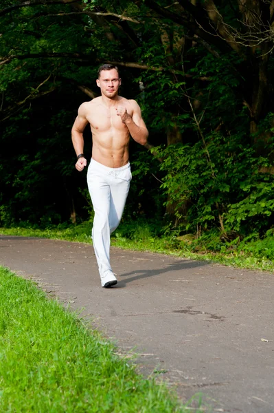 Homem de calças brancas corre na estrada — Fotografia de Stock