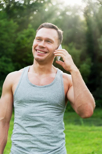 Homem fica com um telefone no parque — Fotografia de Stock