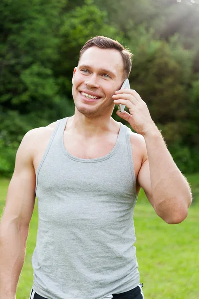 Homem fica com um telefone no parque — Fotografia de Stock