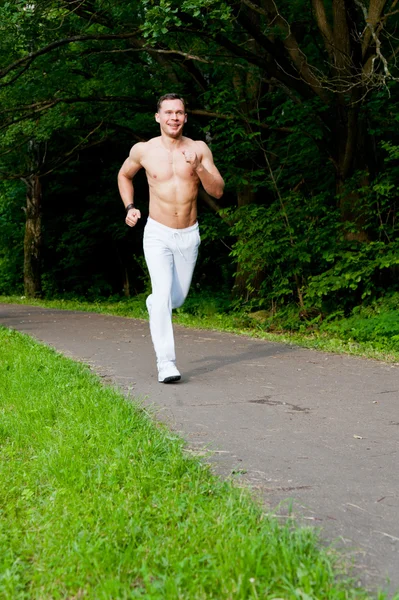 Man in white pants runs on the road — Stock Photo, Image