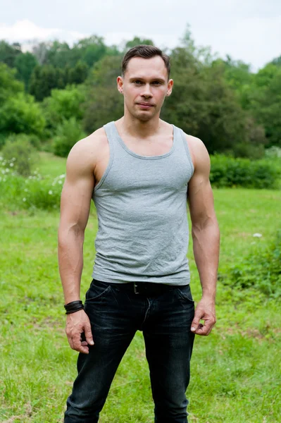 Man in een t-shirt staat op het gras — Stockfoto