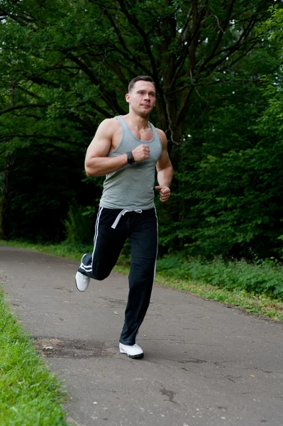 Uomo in pantaloni neri corre sulla strada — Foto Stock