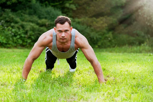 Człowiek robi ćwiczeń fitness na trawie — Zdjęcie stockowe