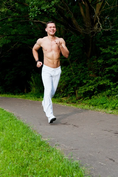 Man in white pants runs on the road — Stock Photo, Image