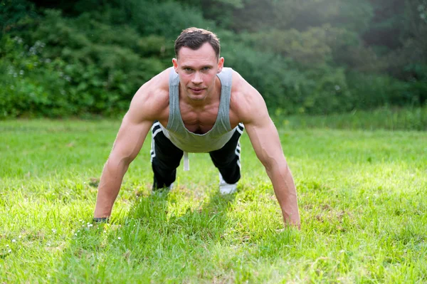 Man gör fitness motion på gräset — Stockfoto