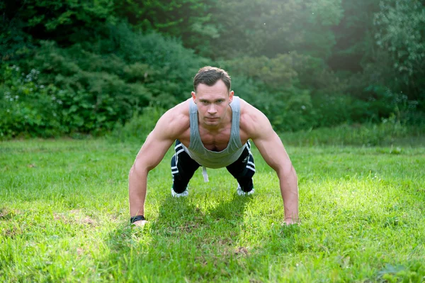 Man gör fitness motion på gräset — Stockfoto