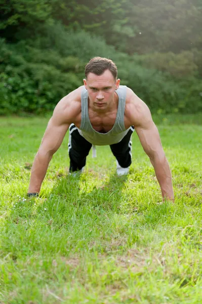 Człowiek robi ćwiczeń fitness na trawie — Zdjęcie stockowe