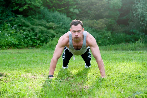 Člověk dělá fitness cvičení na trávě — Stock fotografie