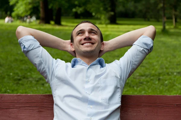 Homem sorridente sentado no banco — Fotografia de Stock