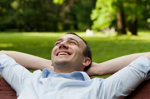 Homme souriant assis sur le banc — Photo