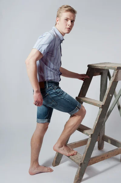 Young man stands near the ladder — Stock Photo, Image